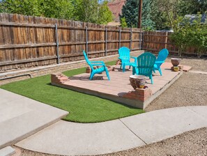 A backyard with a wooden fence, green artificial grass, and blue outdoor furniture.