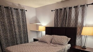 A bedroom with a bed, nightstands, lamps, a ceiling fan, and patterned curtains. - Lovely 4-bedroom house in Flagstaff perfect for your getaway (Flagstaff)