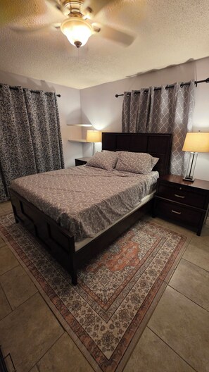 A bedroom with a bed, nightstands, lamps, a ceiling fan, and patterned curtains. - Lovely 4-bedroom house in Flagstaff perfect for your getaway (Flagstaff)