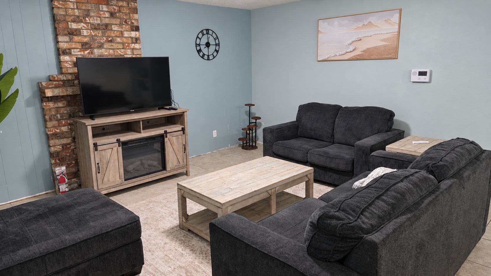 Ein Wohnzimmer mit Fernseher, Sofa, Couchtisch, Kamin und Kunstwerken an der Wand.