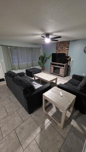 A living room with a sofa set, a coffee table, a TV stand, and a ceiling fan. - Lovely 4-bedroom house in Flagstaff perfect for your getaway (Flagstaff)