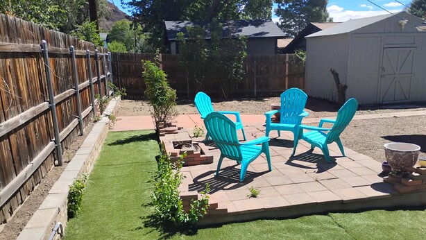 A backyard with a wooden fence, a patio with chairs, and a small garden area. - Lovely 4-bedroom house in Flagstaff perfect for your getaway (Flagstaff)
