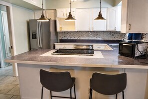 A kitchen with a large island, two pendant lights, a refrigerator, a microwave, and a tiled backsplash. - Lovely 4-bedroom house in Flagstaff perfect for your getaway (Flagstaff)