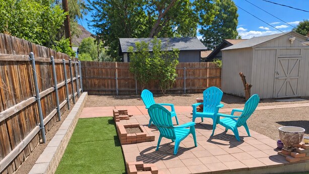 A backyard with a patio area, a wooden fence, and a shed.