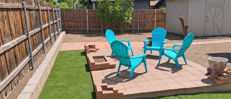 A backyard with a patio area, a wooden fence, and a shed.