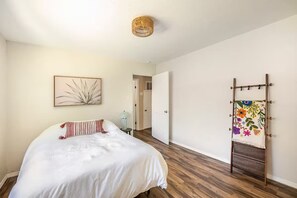 Ein Schlafzimmer mit einem Bett, einer hängenden Pflanze, einer Tür und einem Wandregal.