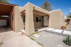 Ein stuckierter Wohnbau mit Garage, überdachter Veranda und kleinem Garten.