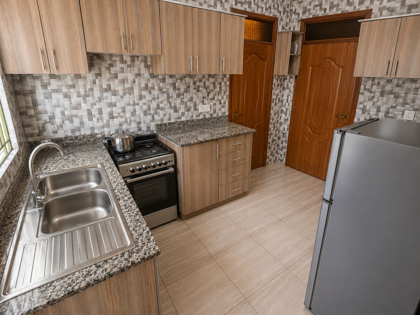 A kitchen with wooden cabinets, a stainless steel sink, a stove, and a refrigerator.
