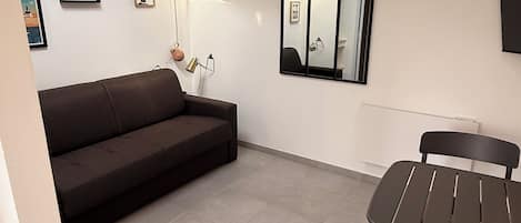 A modern living space with a sofa, a dining table, and a large mirror.