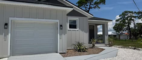 A single-story house with a garage, a small porch, and a gravel driveway.