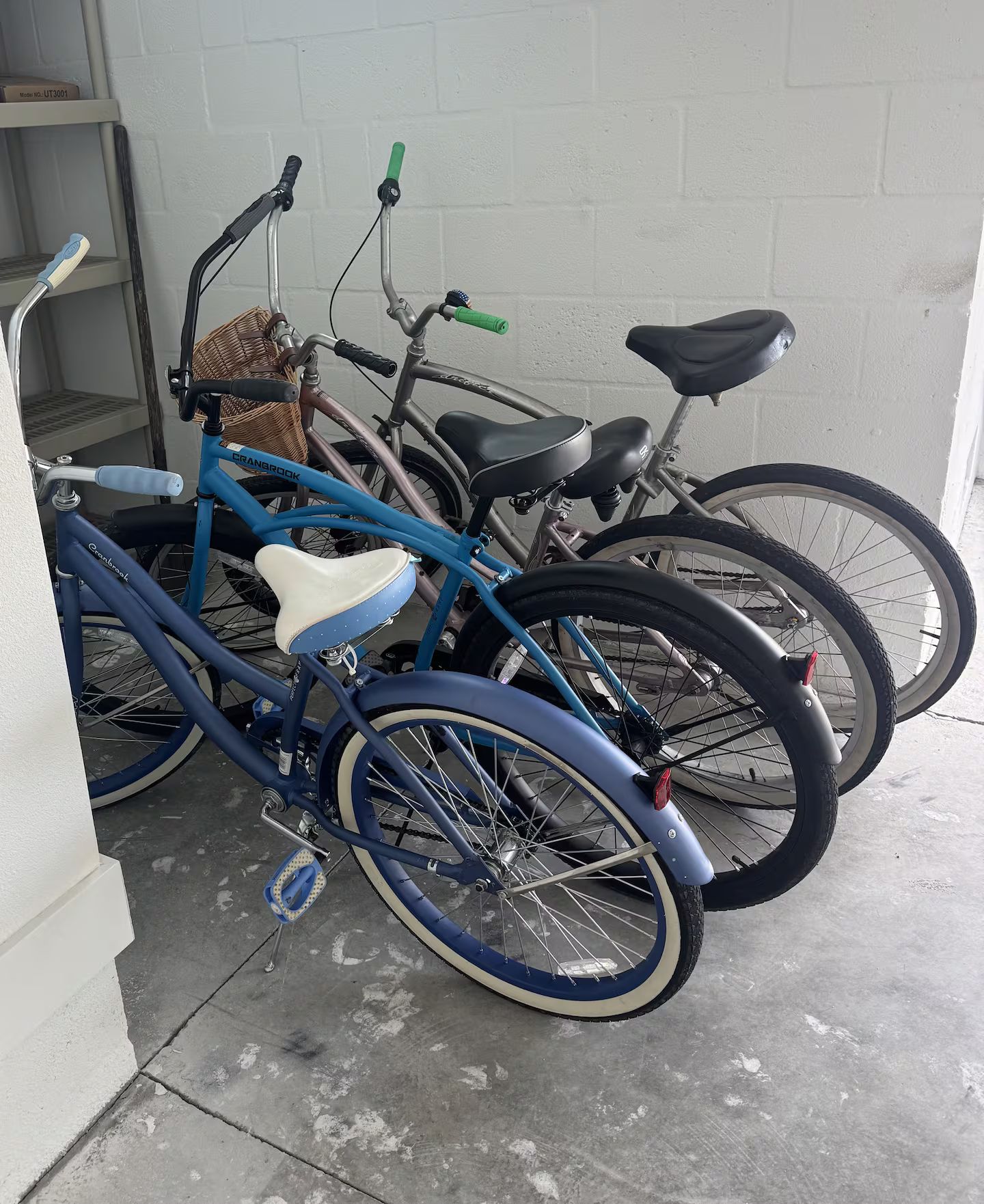 A bicycle leaning against a wall, with a basket attached to the handlebars.
