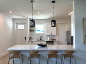 A modern kitchen with a large island, pendant lighting, and a view of the outdoors. - Close to Beaches ~ Downtown Venice ~ Bike Trail ~ Park (Nokomis)