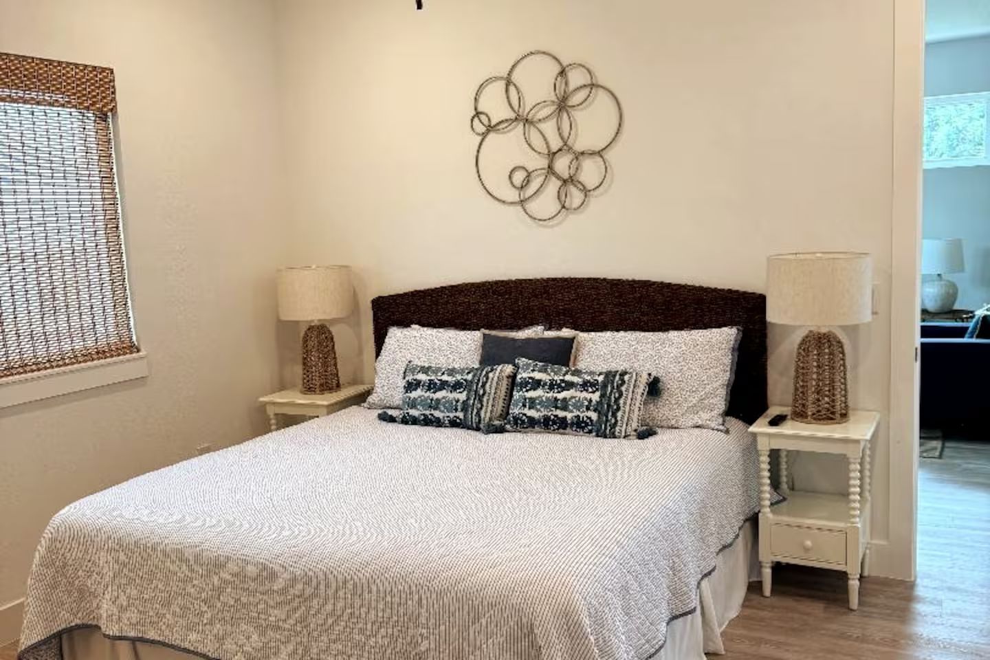 Un dormitorio ordenado con una cama, dos mesitas de noche y un adorno en la pared.