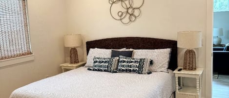 Une chambre à coucher bien rangée, avec un lit, deux tables de chevet et un élément décoratif mural.