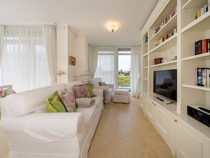 A living room with a white sofa, a television, and a bookshelf. - Holiday Apartment With 2 Bedrooms (Kuehlungsborn)