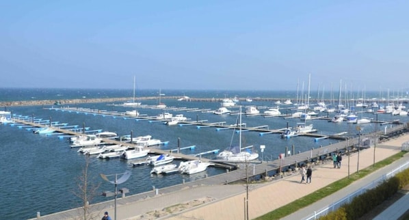 A marina with numerous boats docked at piers, a walkway along the water, and a clear sky. - Holiday Apartment With 2 Bedrooms (Kuehlungsborn)