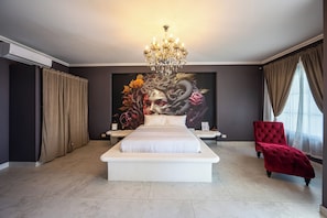 A bedroom with a large bed, a chandelier, a red chair, and a painting on the wall. - The Palace Villa Luxury Jaco Experience Olympus: Greek Gods, Jacuzzi, Pool, Bar (Jacó)
