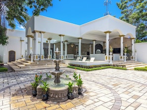 A courtyard with a central fountain, white columns, and a covered seating area. - The Palace Villa Luxury Jaco Experience Olympus: Greek Gods, Jacuzzi, Pool, Bar (Jacó)