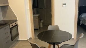 A modern kitchen with a built-in oven and a dining area with a round table and four chairs. - Villa Art Dome (Paralia)