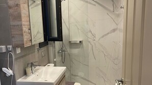 A modern bathroom with a marble shower, a sink with a mirror, and a toilet. - Villa Art Dome (Paralia)