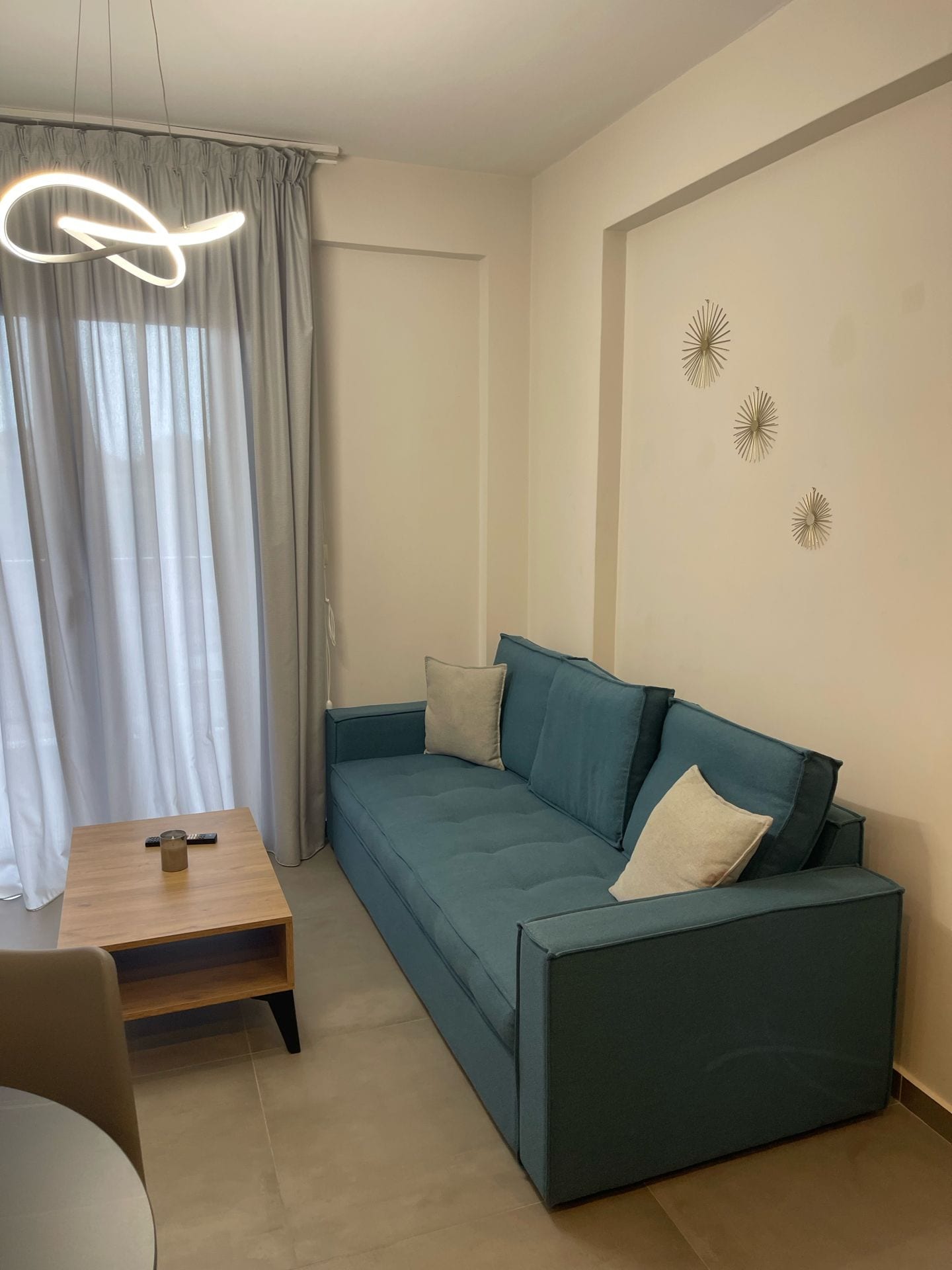 Uma sala de estar moderna com um sofá verde-água, uma mesa de centro de madeira e um controle remoto sobre ela.