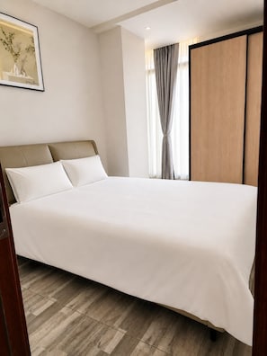 A neatly made bed in a hotel room with a headboard, a wooden wardrobe, and a framed picture on the wall. - Spacious 3BR Serviced Apartment Near Bole Airport (Addis Ababa)