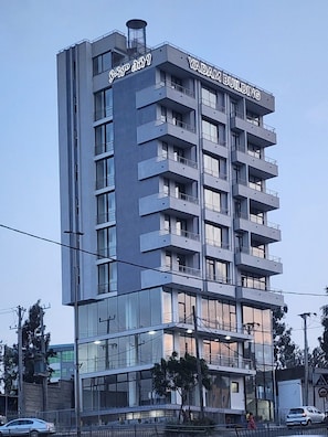 A multi-story building with balconies, a sign reading 'YADAM BUILDING,' and a visible entrance with glass doors. - Spacious 3BR Serviced Apartment Near Bole Airport (Addis Ababa)