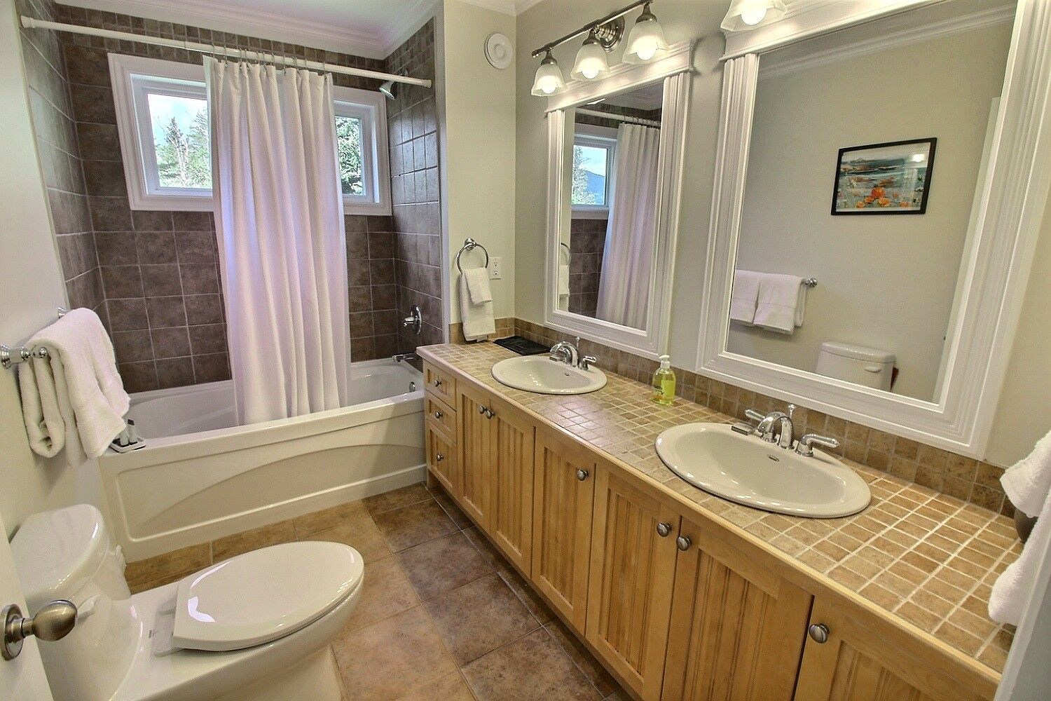 A bathroom with a bathtub, two sinks, a toilet, and a shower curtain.