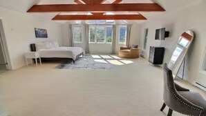 Une chambre spacieuse avec un grand lit, un coin salon et une télévision.