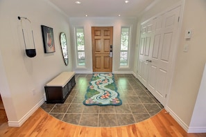 A hallway with a bench, a wooden door, and a patterned rug.