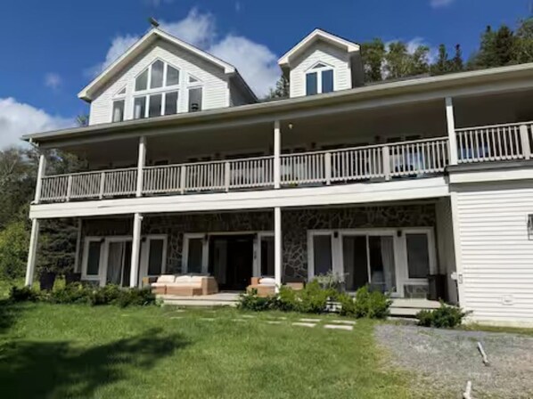 Une maison à deux étages dotée d’un balcon, d’un porche couvert et d’une façade en pierre.