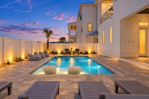 A swimming pool with lounge chairs and a table, surrounded by a white fence and a two-story building. - Beach Views-Private Pool-Central PCB (Panama City Beach)