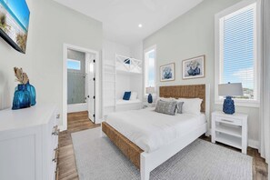 A bedroom with a bed, bedside tables, a wardrobe, a shower area, and artwork on the walls. - Beach Views-Private Pool-Central PCB (Panama City Beach)