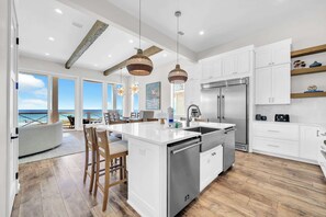 A modern kitchen with a central island, stainless steel appliances, and a view to the outside. - Beach Views-Private Pool-Central PCB (Panama City Beach)