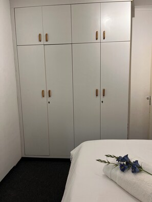 A bedroom with a bed, a wardrobe with wooden handles, and a small bouquet of flowers on the bed.
