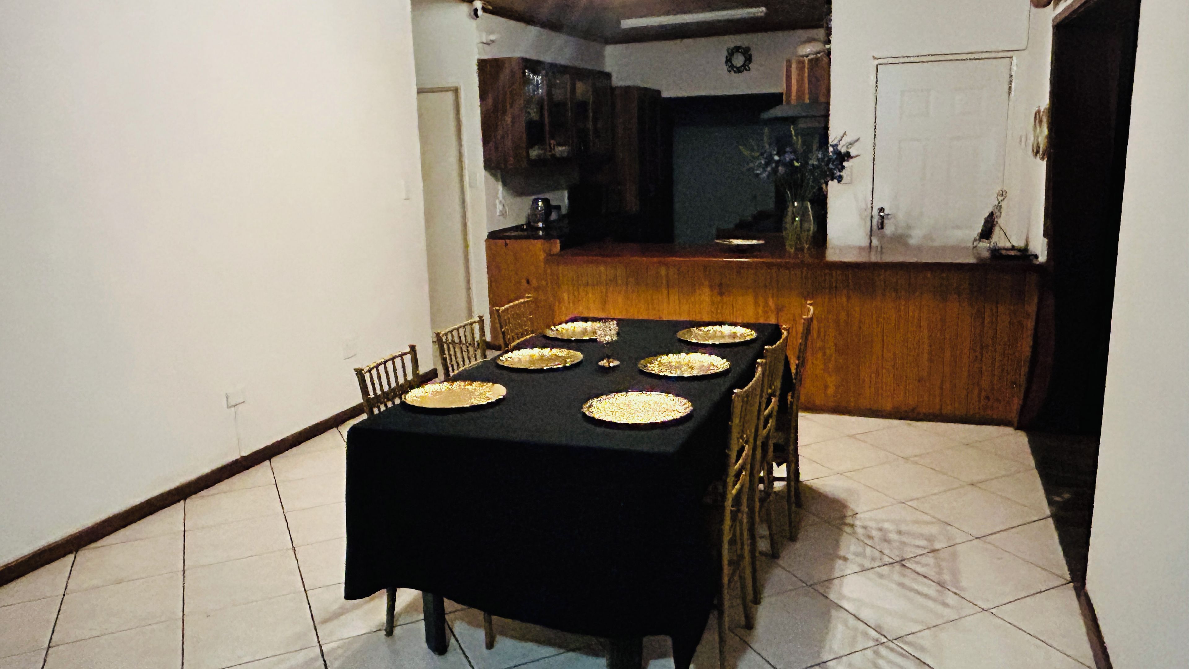 Un comedor con mantel negro, seis sillas y seis platos redondos sobre la mesa.