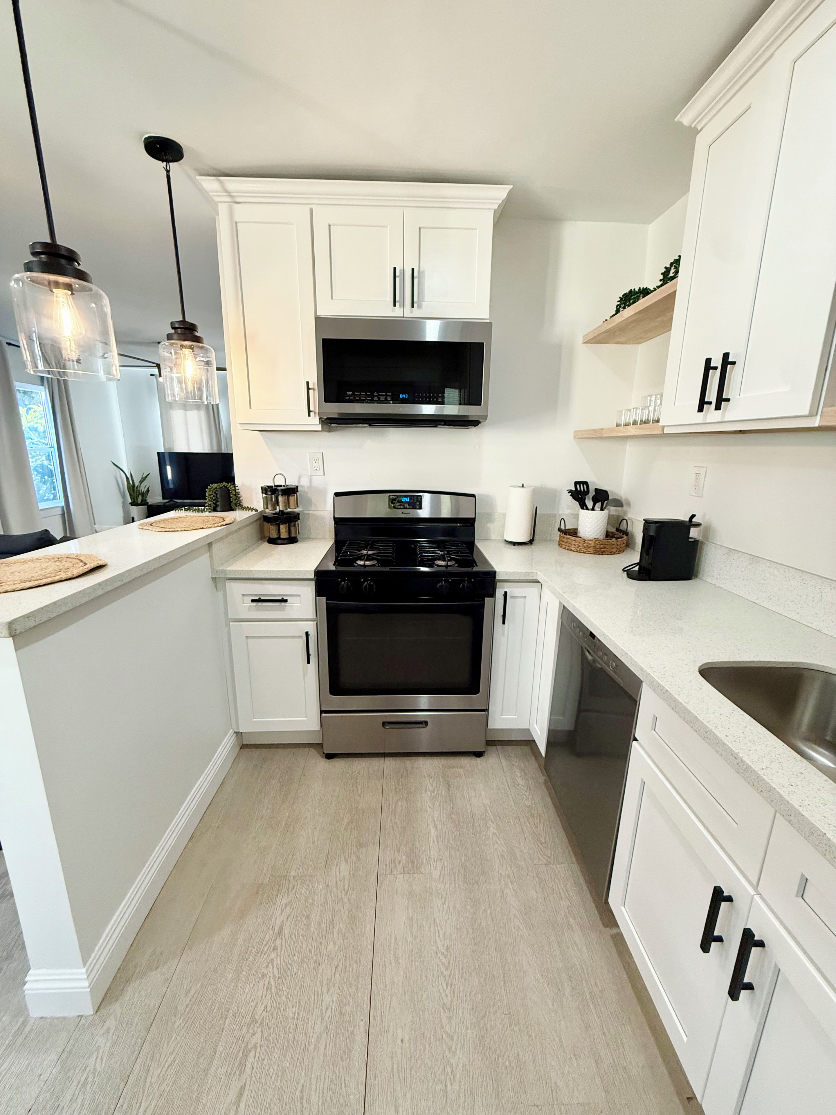 A modern kitchen with white cabinetry, a stainless steel stove, and a microwave above it.