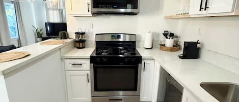 A modern kitchen with white cabinetry, a stainless steel stove, and a microwave above it.