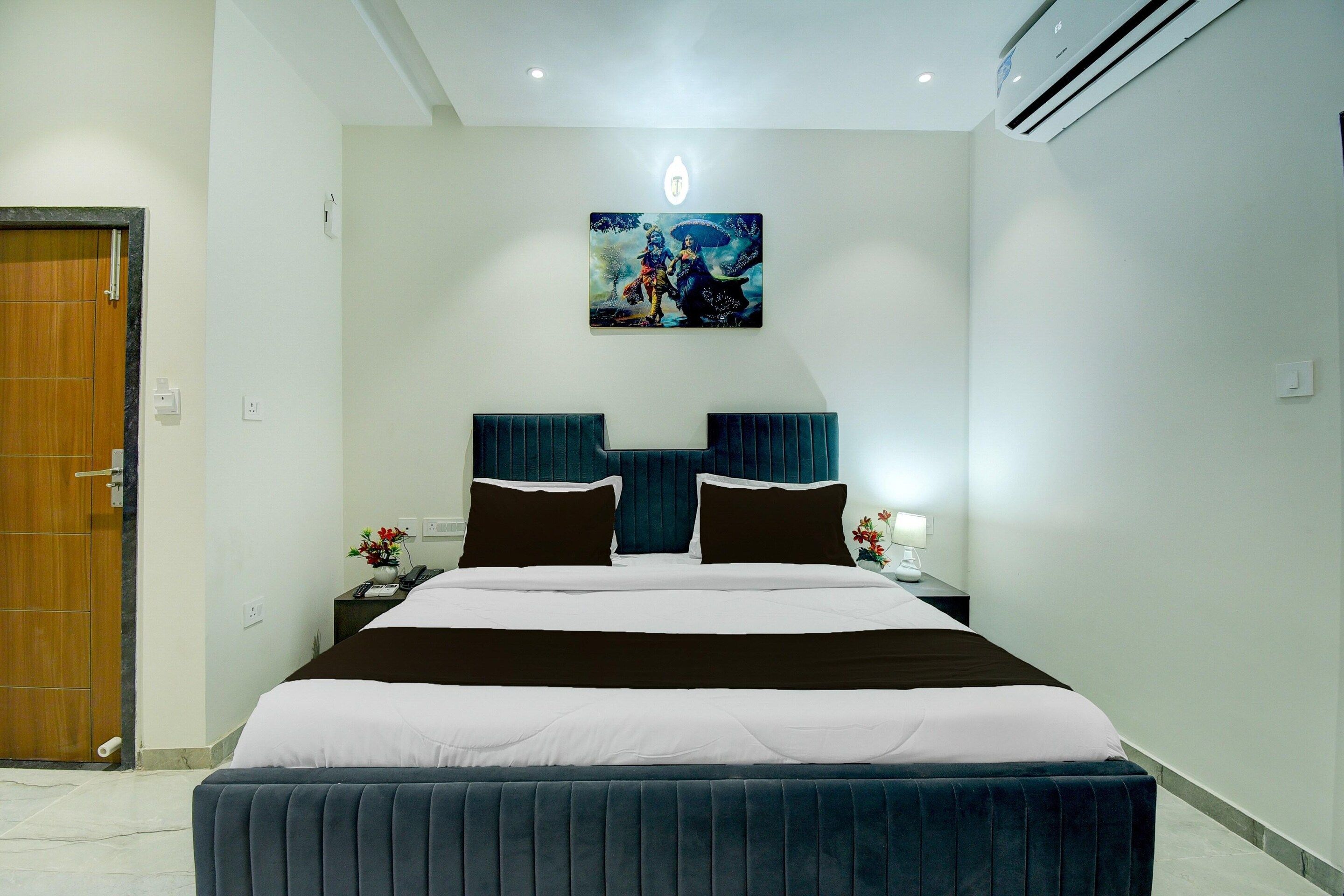 Habitación de hotel con una cama, dos mesitas de noche, una lámpara de noche, un aire acondicionado de pared y un cuadro sobre la cama.