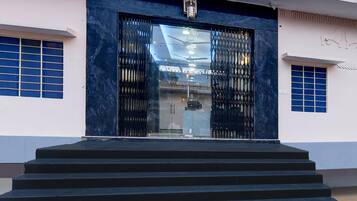 A building entrance with a set of stairs leading up to a glass door with metal grilles.