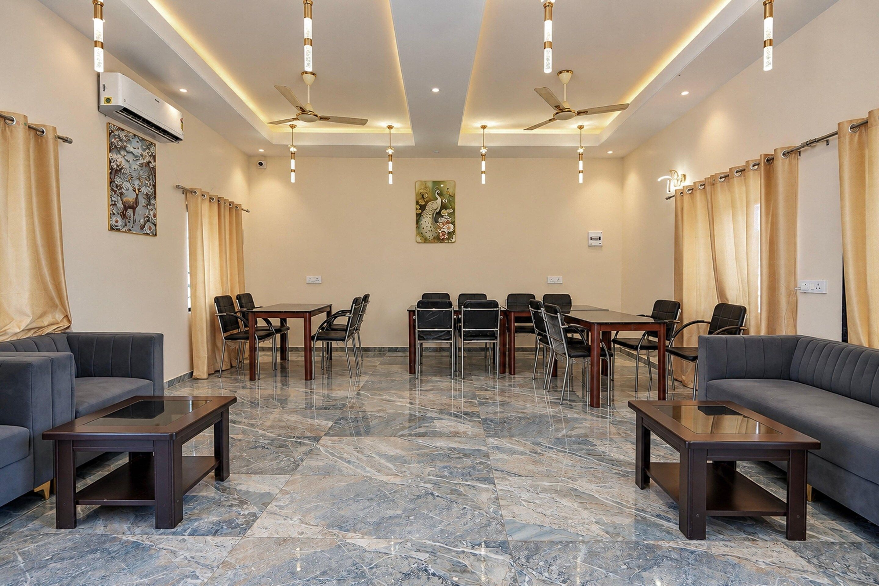 A conference room with a marble floor, black chairs, a wooden table, and ceiling fans.