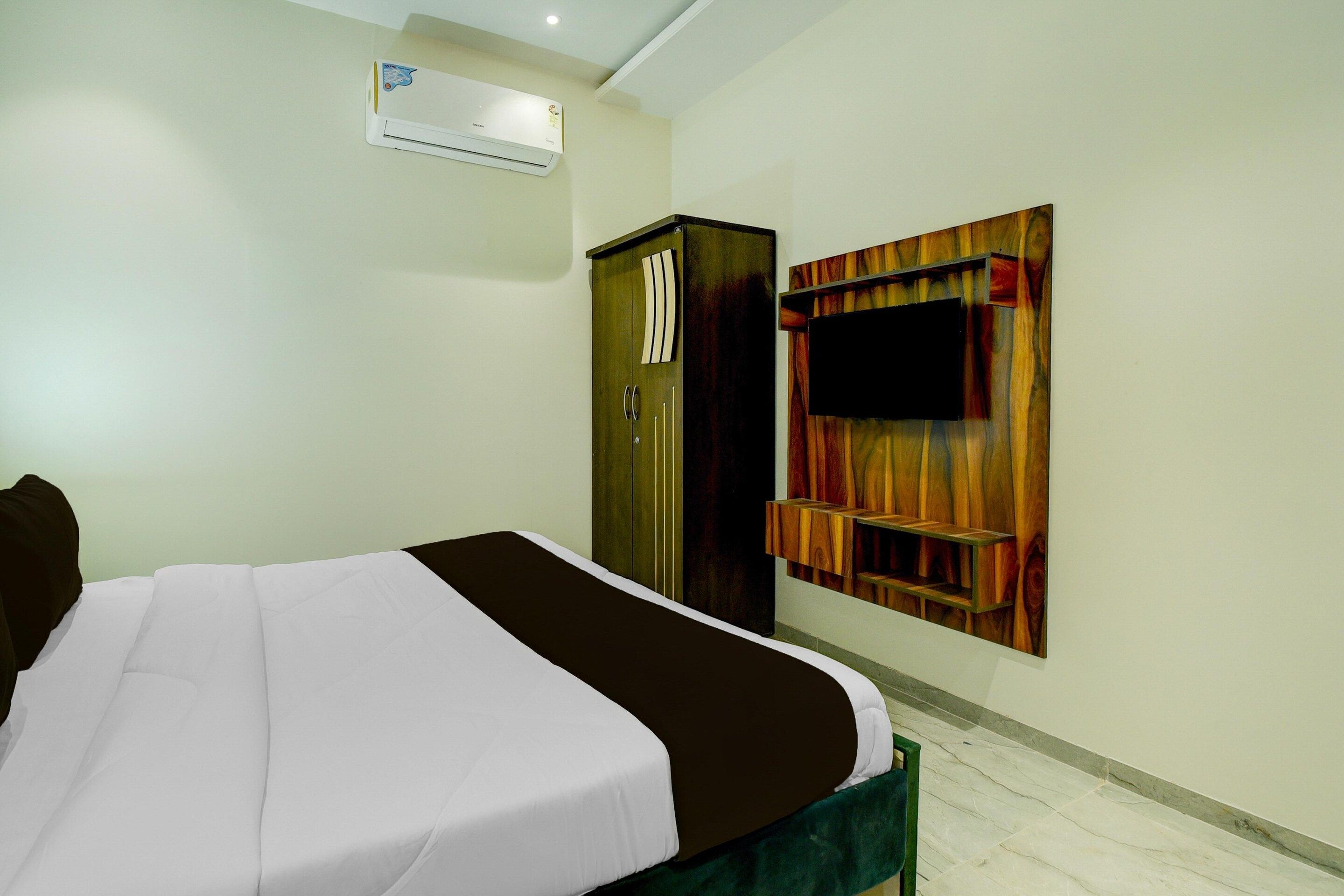 Een hotelkamer met een bed, garderobe en een televisie aan de muur.