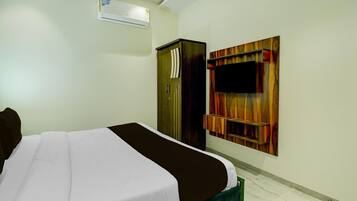 Een hotelkamer met een bed, garderobe en een televisie aan de muur.