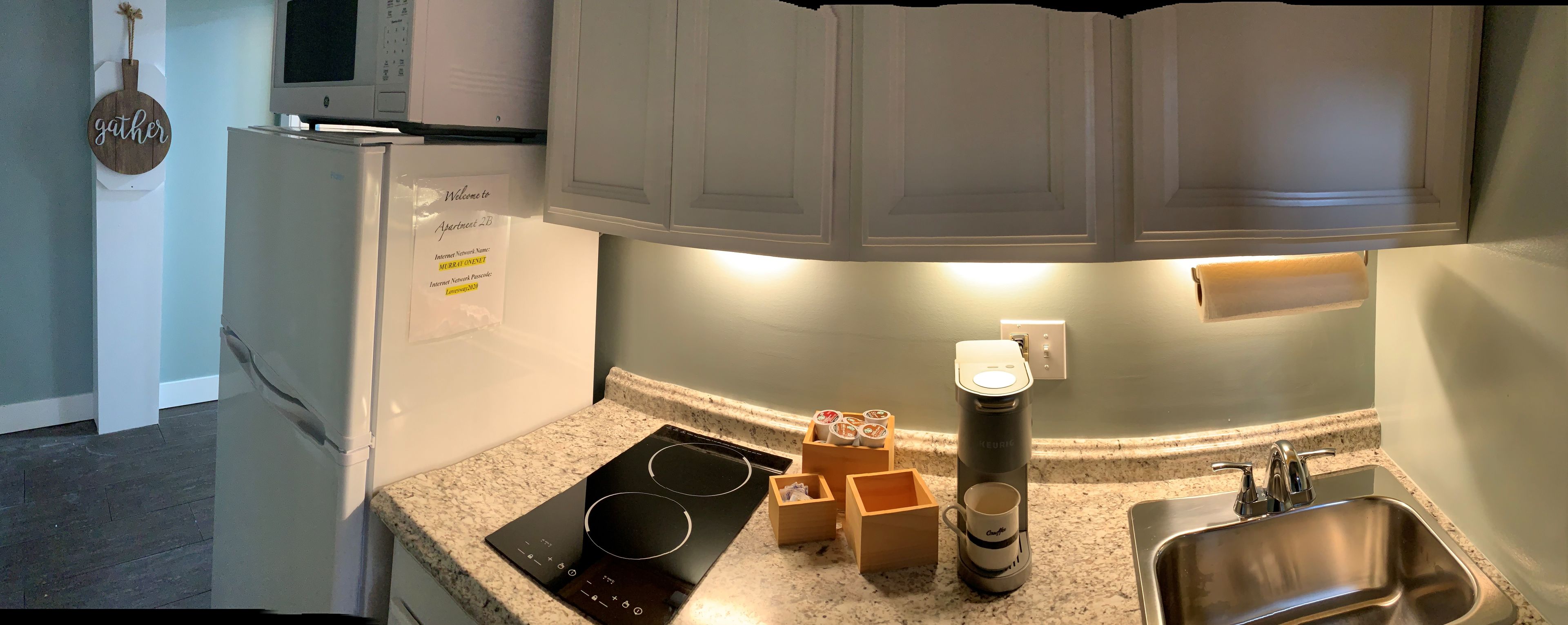 A kitchen with a built-in microwave, a coffee maker, and a sign indicating the apartment number.