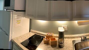 A kitchen with a built-in microwave, a coffee maker, and a sign indicating the apartment number.