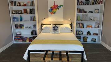 A bedroom with a bed, two bookshelves, a map, and a variety of books and decorative items.