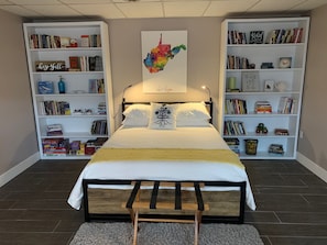 Ein Schlafzimmer mit einem Bett, zwei Bücherregalen, einer Karte und verschiedenen Büchern sowie Dekorationselementen.