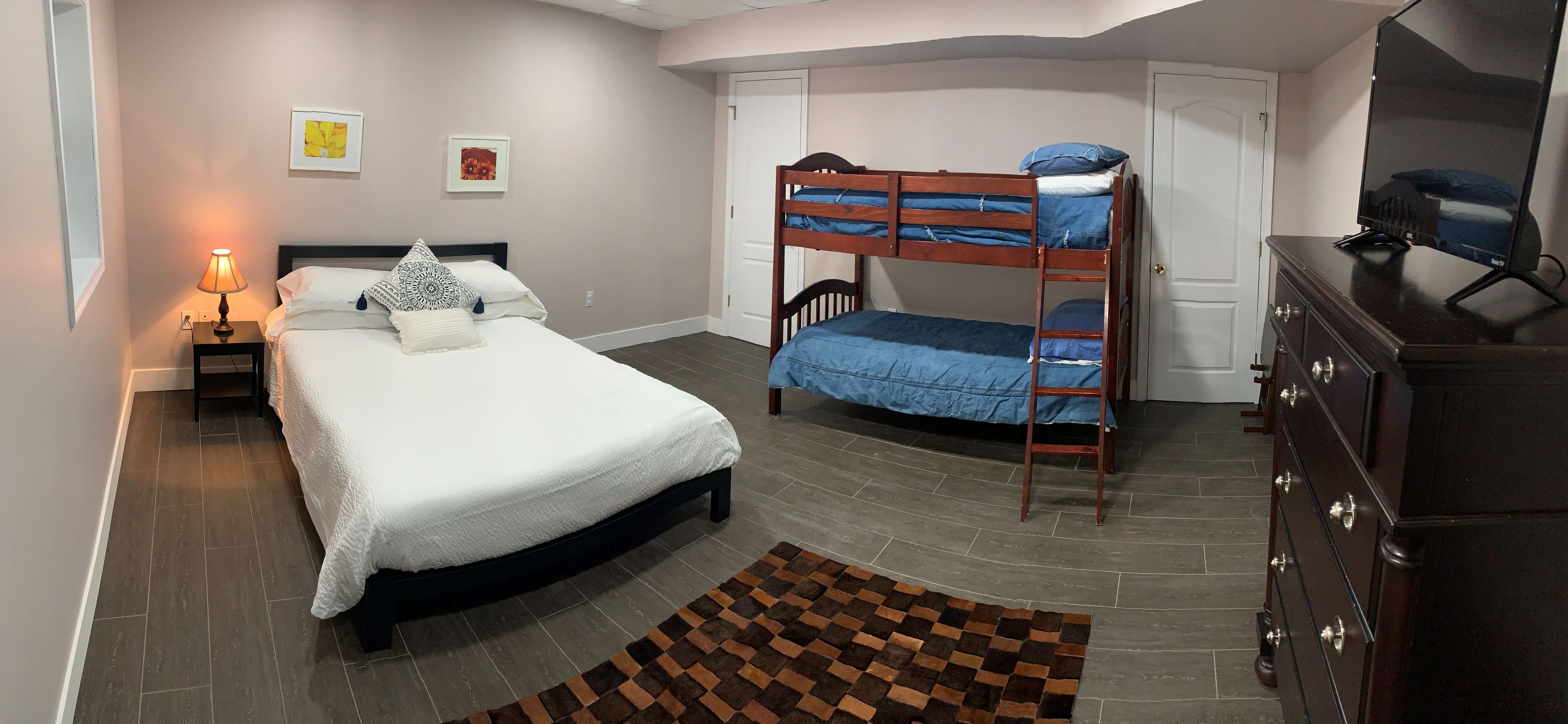 Un dormitorio con una cama individual, una cama litera, un aparador, una lámpara y una alfombra.