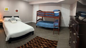 Una camera da letto con un letto singolo, un letto a castello, un comò, una lampada e un tappeto.