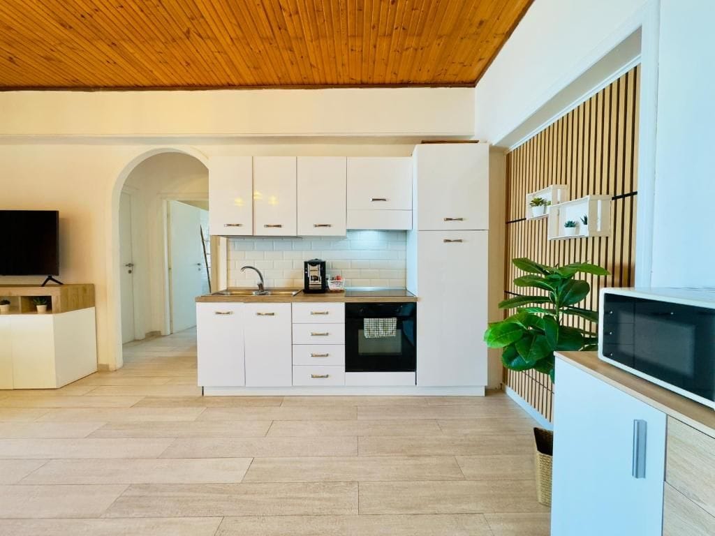 A modern kitchen with white cabinets, a built-in oven, and a wooden ceiling.